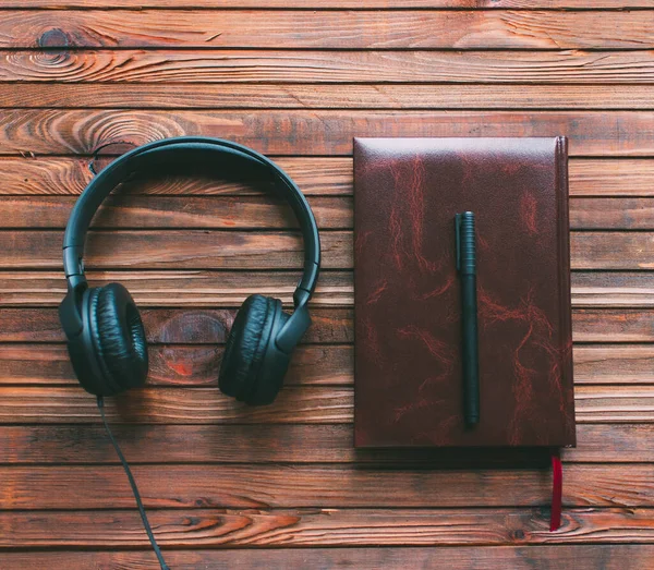 茶色の木製の背景に革のノートブック ペンとヘッドフォン 音楽のテーマ — ストック写真