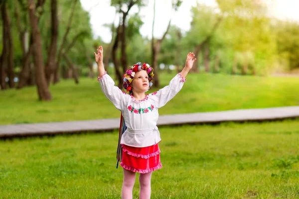 緑の背景にウクライナの民族衣装の若い女の子の肖像画 屋外だ 抱擁のために手を伸ばし — ストック写真