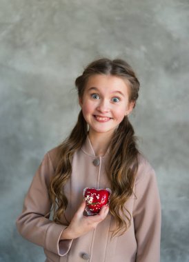  Elinde kırmızı kalp şeklinde bir pasta tutan neşeli bir kızın portresi..