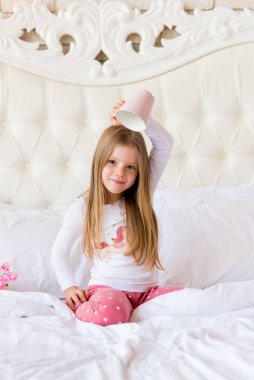 Küçük tatlı kız elinde kupa tutuyor.