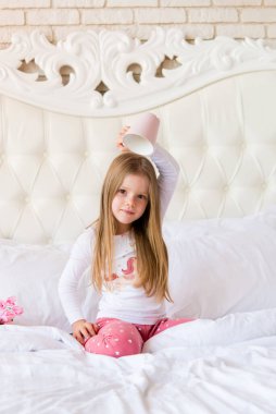 Küçük tatlı kız elinde kupa tutuyor.