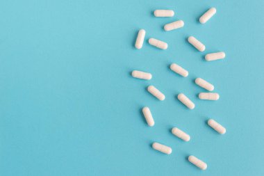 Mavi arka planda beyaz kapsül hapları. Metin için kopyalama alanı olan tıbbi arkaplan.