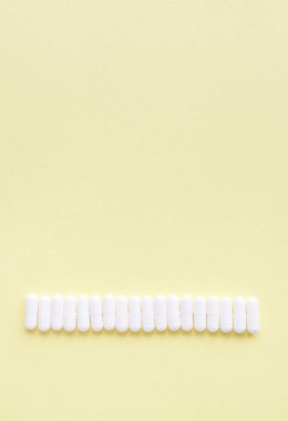 Sarı arka planda beyaz kapsüller. Metin için kopyalama alanı olan tıbbi arkaplan.