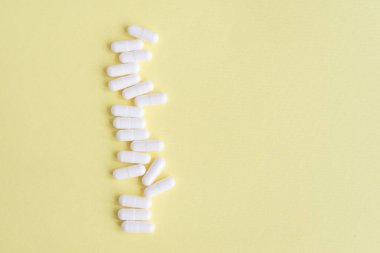 Sarı arka planda beyaz kapsüller. Metin için kopyalama alanı olan tıbbi arkaplan.