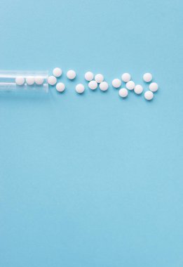 Farklı beyaz haplar ve mavi arka planda plastik bir kap. Tıbbi tema.