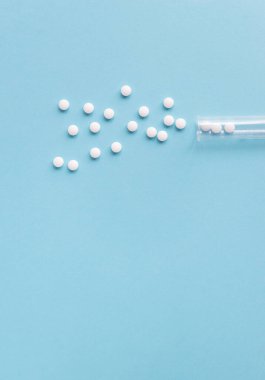 Farklı beyaz haplar ve mavi arka planda plastik bir kap. Tıbbi tema.