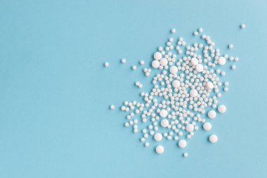 Mavi pastel arka planda beyaz haplar. Yuvarlak ve bezelye haplarını yakından çek. Sağlık ve İlaç.