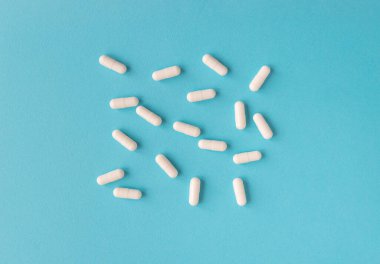 Mavi arka planda beyaz kapsül hapları. Metin için kopyalama alanı olan tıbbi arkaplan.