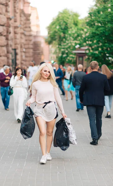 Şehrin arka sokaklarında sokak kıyafetleri içinde mutlu bir kadın. Alışveriş torbaları..