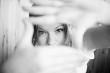 Ön planda bir kadın portresi, bir el çerçevesi. Gözlerinde aksan var. Siyah ve beyaz.