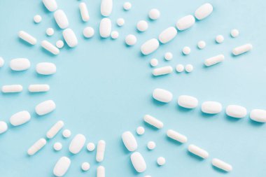 Pastel arka planda beyaz haplar. Kapsüller ve yuvarlak haplar yakın plan. Sağlık ve İlaç Hizmetleri.