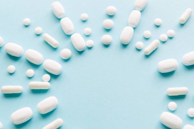 Pastel arka planda beyaz haplar. Kapsüller ve yuvarlak haplar yakın plan. Sağlık ve İlaç Hizmetleri.