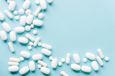 Pastel arka planda beyaz haplar. Kapsüller ve yuvarlak haplar yakın plan. Sağlık ve İlaç Hizmetleri.