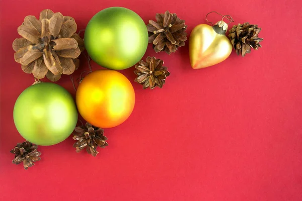 Grüne Gelbe Weihnachtskugeln Zapfen Und Dekorative Kugeln Auf Rotem Hintergrund — Stockfoto