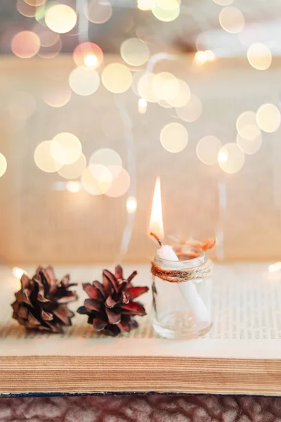Burning Candle Glass Jar Cones Background Old Open Book Festive — Stock Photo, Image