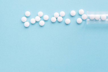 Farklı beyaz haplar ve mavi arka planda plastik bir kap. Tıbbi tema.