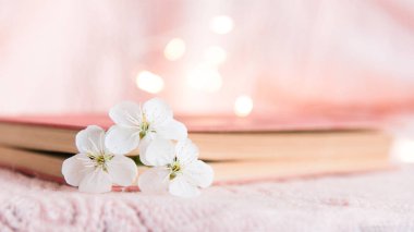 Pembe arka planda beyaz küçük çiçekli eski bir kitap.