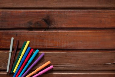 school stationery with markers and other supplies on brown wooden background. back to school concept