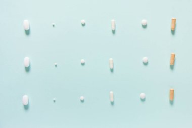 Mavi masaya saçılmış beyaz haplar. Reklam, web geçmişi ya da diğer fikirler için özel teklifler alın. Tıbbi, eczane ve sağlık hizmetleri konsepti. Uzayı kopyala Metin veya logo için boş yer.