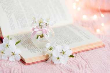 Pembe arka planda beyaz çiçekli açık bir kitap