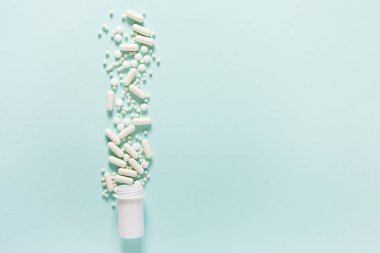 Mavi masaya saçılmış beyaz haplar. Reklam, web geçmişi ya da diğer fikirler için özel teklifler alın. Tıbbi, eczane ve sağlık hizmetleri konsepti. Uzayı kopyala Metin veya logo için boş yer