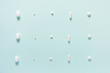 Mavi masaya saçılmış beyaz haplar. Reklam, web geçmişi ya da diğer fikirler için özel teklifler alın. Tıbbi, eczane ve sağlık hizmetleri konsepti. Uzayı kopyala Metin veya logo için boş yer