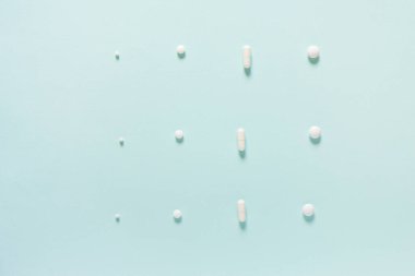 Mavi masaya saçılmış beyaz haplar. Reklam, web geçmişi ya da diğer fikirler için özel teklifler alın. Tıbbi, eczane ve sağlık hizmetleri konsepti. Uzayı kopyala Metin veya logo için boş yer