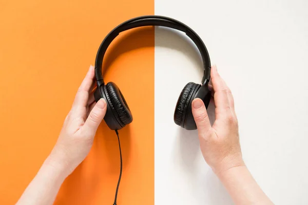 Hands Holding Headphones Bicolor Orange White Background View Copy Space — ストック写真