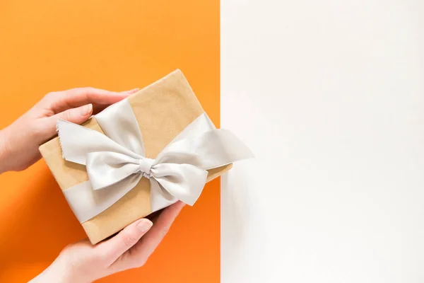 Hands Holding Gift Box Ribbon Bow Bicolor Orange Gray Background — Foto de Stock
