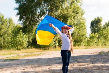 Ulusal Ukrayna kıyafetleri içinde küçük bir kız - vyshyvanka. Ukrayna, doğanın çocuğu. Ukrayna bayrağının ellerinde.