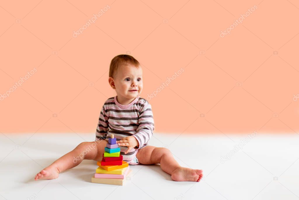 little child playing with toys on a plain background. Education and learning game concept with copy space.