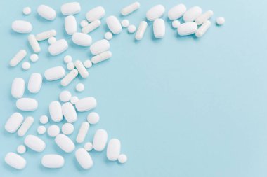 white pills on blue table. Medical, pharmacy and healthcare concept. Copy space.  Place for text or logo. Mock up for special offers as advertising or other ideas.