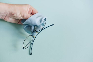 hand wipes glasses with a napkin on a blue background. Glass cleaning cloth, napkin