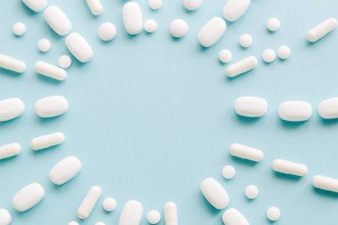 Mavi masaya saçılmış beyaz haplar. Reklam, web geçmişi ya da diğer fikirler için özel teklifler alın. Tıbbi, eczane ve sağlık hizmetleri konsepti. Uzayı kopyala Metin veya logo için boş yer.