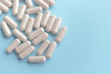 white pills on blue table. Medical, pharmacy and healthcare concept. Copy space. Place for text or logo. Mock up for special offers as advertising or other ideas.