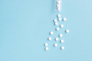 Mavi masaya saçılmış beyaz haplar. Reklam, web geçmişi ya da diğer fikirler için özel teklifler alın. Tıbbi, eczane ve sağlık hizmetleri konsepti. Uzayı kopyala Metin veya logo için boş yer