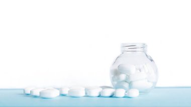 Mavi masaya saçılmış beyaz haplar. Reklam, web geçmişi ya da diğer fikirler için özel teklifler alın. Tıbbi, eczane ve sağlık hizmetleri konsepti. Uzayı kopyala Metin veya logo için boş yer