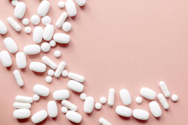 Pastel arka planda beyaz haplar. Kapsüller ve yuvarlak haplar yakın plan. Sağlık ve İlaç Hizmetleri.