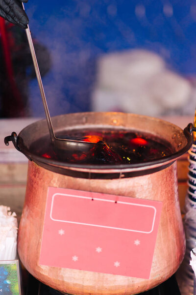Traditional mulled wine, a winter street drink, prepared and heated in a pot in winter at a street shop