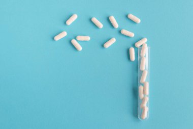 Mavi arka planda beyaz haplar. Reklam, web geçmişi ya da diğer fikirler olarak sunulan özel modeller. İlaç, eczane ve sağlık hizmetleri kavramı. Uzayı kopyala Metin veya logo için boş boşluk