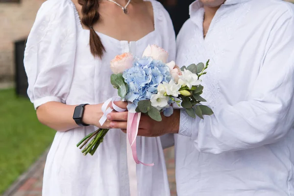 花嫁と新郎はリボンで結婚式の花束を保持 — ストック写真