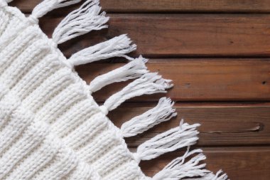 Winter knitted white scarf on a wooden background. Plaid. Warm and cozy in winter.