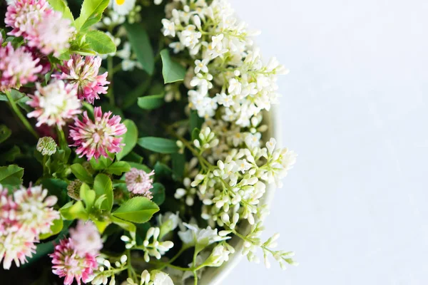 春天的花朵盛开在桌子上的一个圆形花瓶里 桌上有一张白色桌布 一束鲜花和一张精致的花牌 — 图库照片