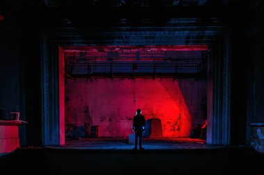 Ürkütücü terk edilmiş tiyatro sahnesindeki adam..