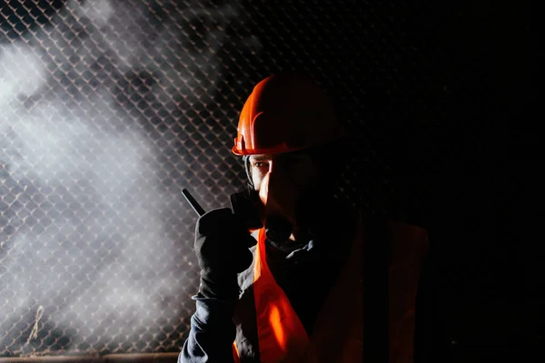 Людина в респіраторі розмовляє про пікі-талькі під час пожежі в промисловому будинку — стокове фото