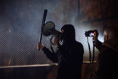 Yarasa ve megafonla maskeli bir asi. Gazeteciler resim yapıyor.