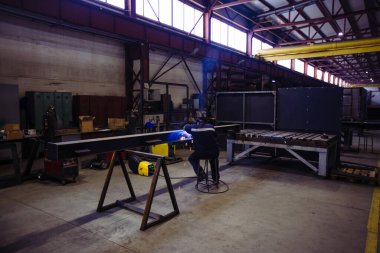 Koruyucu maske takan fabrika işçisi demir parçaları kaynaştırıyor..