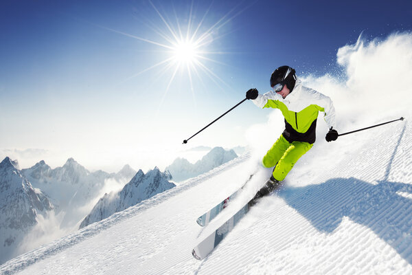 Лыжник в горах, подготовленные трассы и солнечный день
