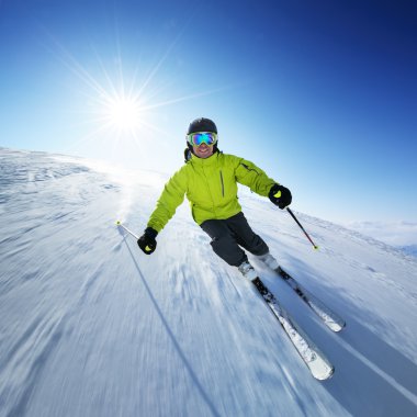 Skier in mountains, prepared piste and sunny day clipart