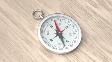 Silver compass on the wooden table, pointing direction to the north